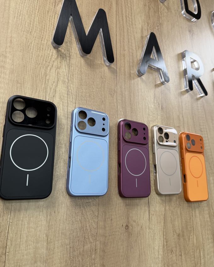 Cinque cover MagSafe colorate sulla parete in legno con le lettere del Lido Market